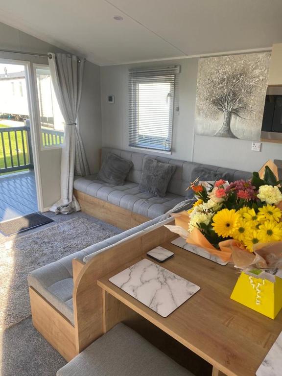 a living room with a couch and a table with flowers at Modern 3 bedroom caravan near the beach in Walton-on-the-Naze