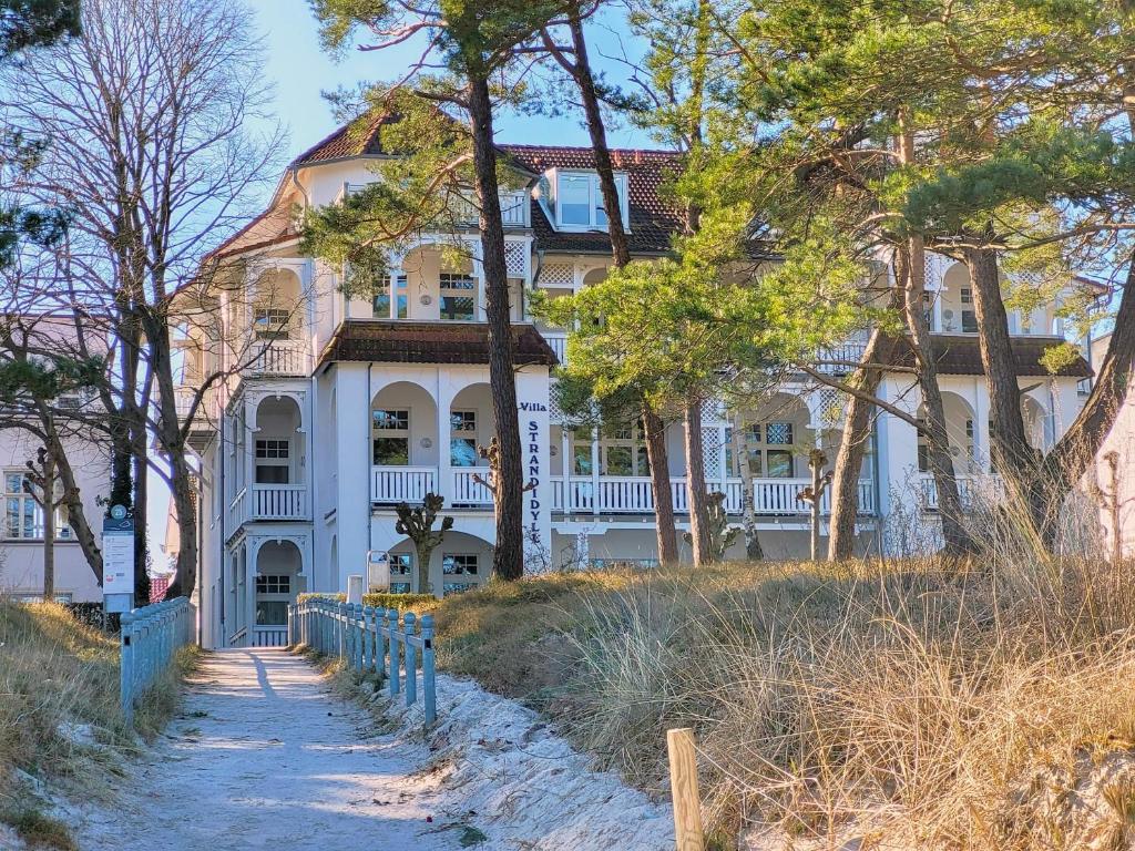 een groot wit huis op een heuvel met bomen bij Villa Strandidyll in Binz - WG 11 mit Meerblick und zwei Balkonen in Binz