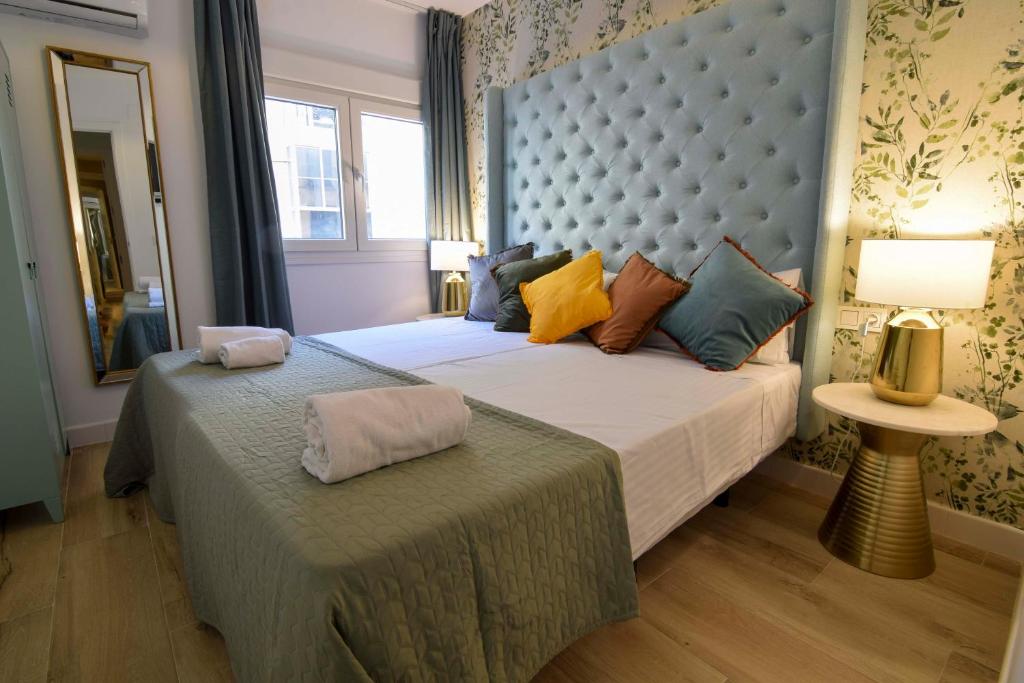 a bedroom with a large bed with a blue headboard at Letmalaga Square Merced in Málaga
