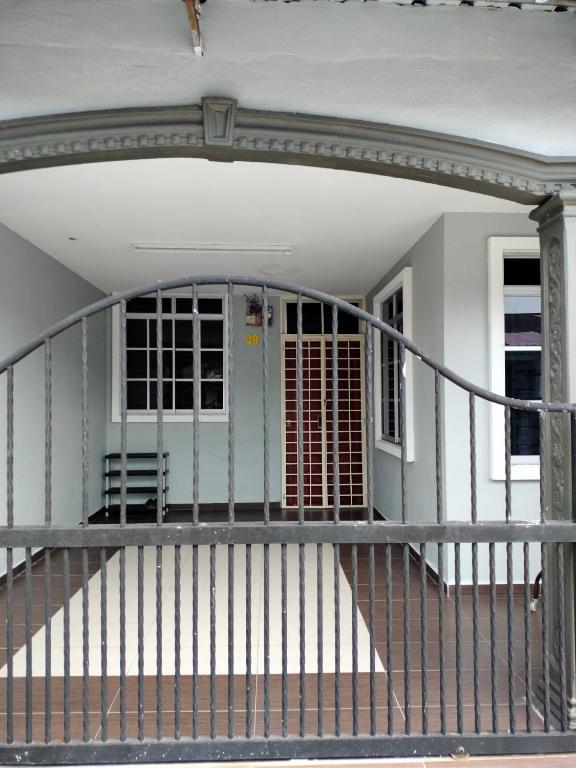 une terrasse couverte à l'avant d'une maison avec une balustrade en métal dans l'établissement Rizki Homestay, à Nibung Tebal