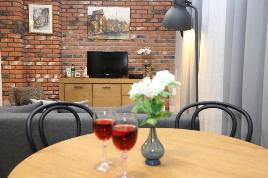 una mesa con dos copas de vino y un jarrón de flores en Old Gdansk No 8 en Gdansk