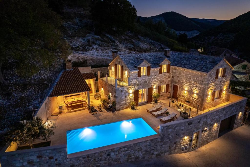 una vista aérea de una casa de piedra con piscina en New Villa Ani! Traditional and luxurious 4-bedroom villa with heated pool and sea views, en Postira