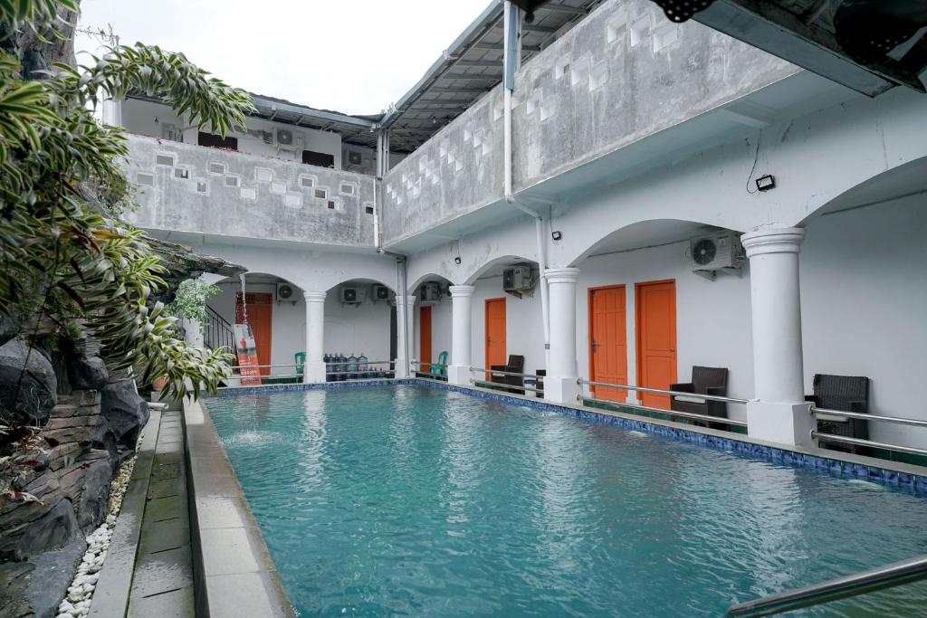 a swimming pool in a building with blue water at RedDoorz Syariah near Exit Toll Puncak in Bogor