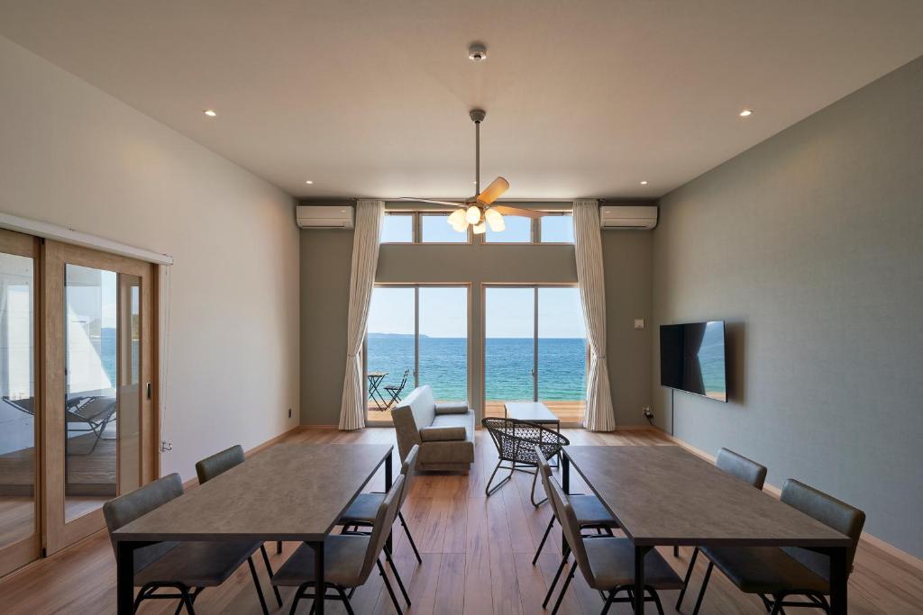 uma sala de jantar com mesas e cadeiras e vista para o oceano em ALFACIO RESORT STAY ITOSHIMA em Itoshima