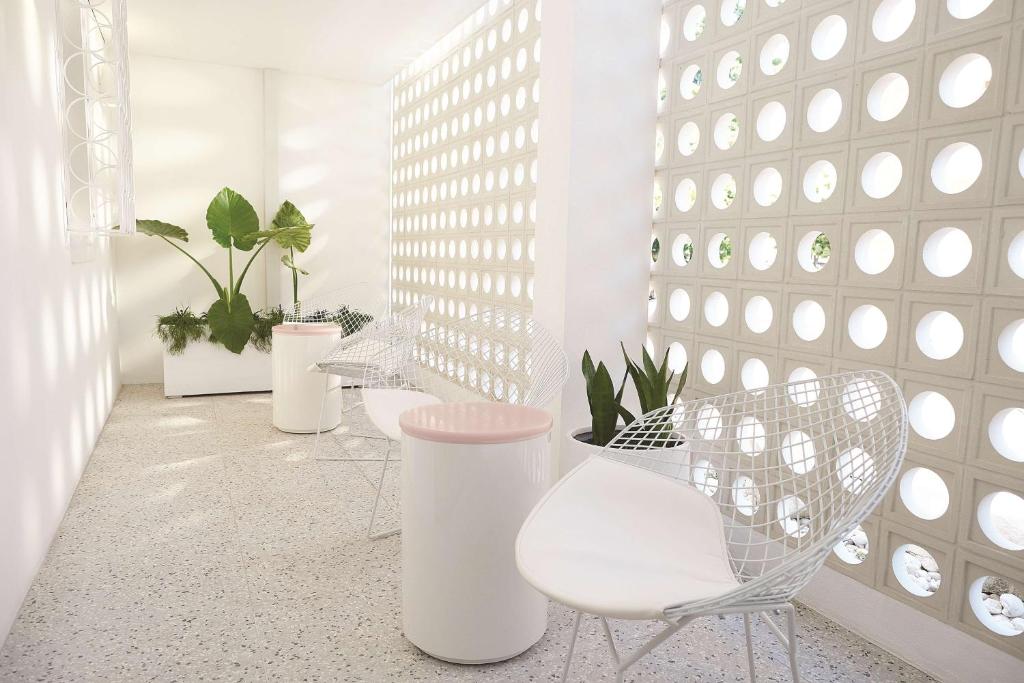 a room with white chairs and a wall with plants at Adina Apartment Hotel Chippendale in Sydney