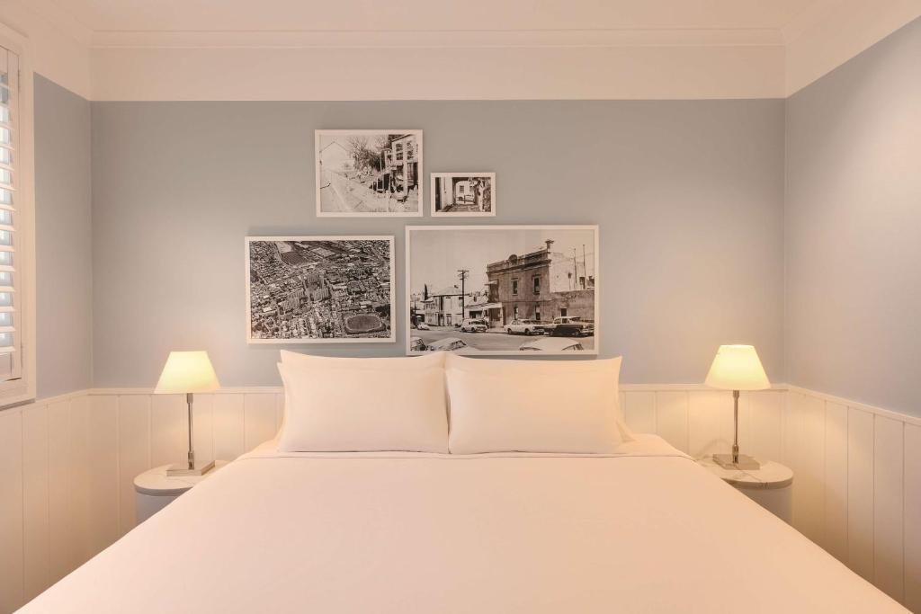a bedroom with a large white bed with two lamps at Adina Apartment Hotel Chippendale in Sydney