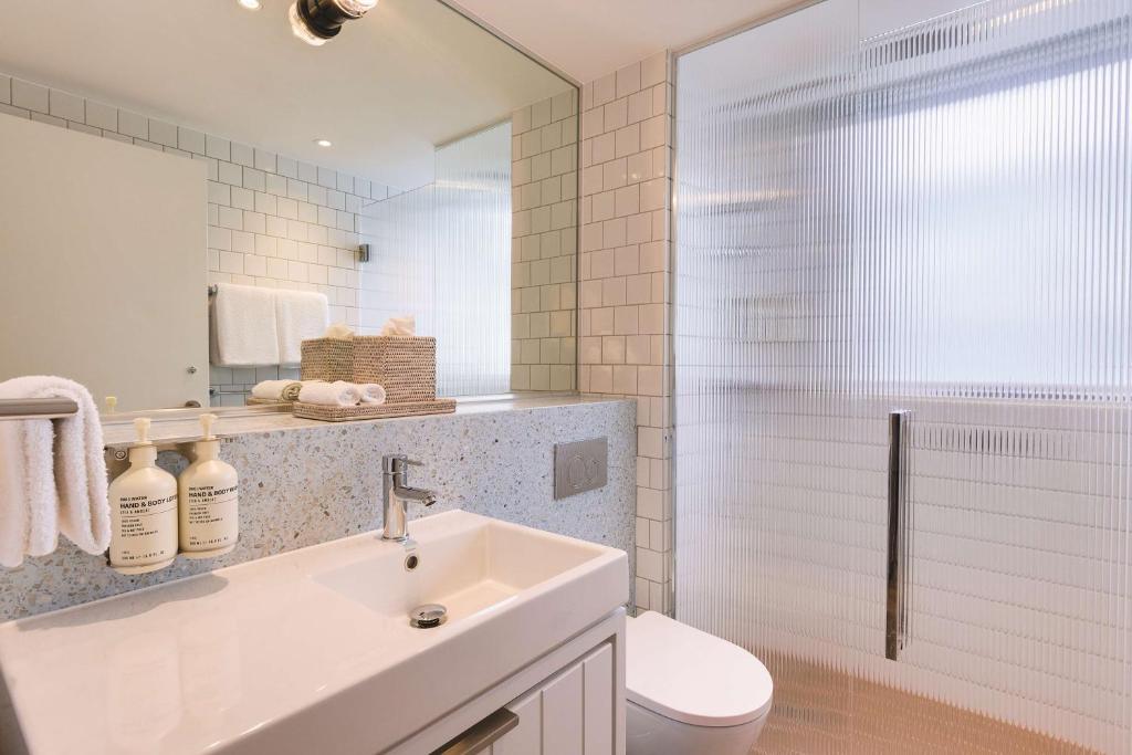 a bathroom with a sink and a toilet and a mirror at Adina Apartment Hotel Chippendale in Sydney