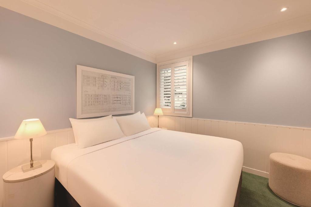 a white bedroom with a white bed and a window at Adina Apartment Hotel Chippendale in Sydney