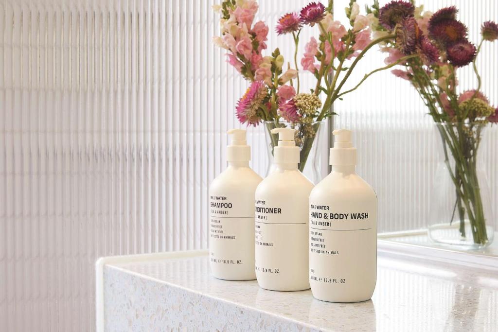 a group of three bottles sitting on a table with flowers at Adina Apartment Hotel Chippendale in Sydney