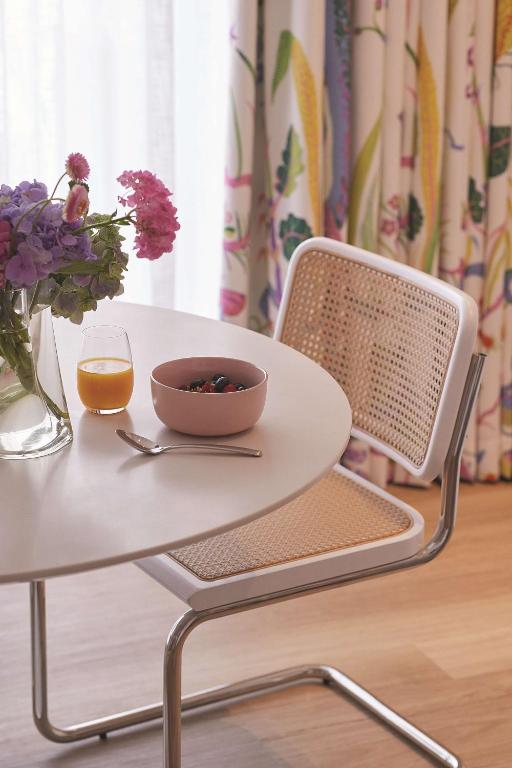 a table with a bowl of flowers and a glass of orange juice at Adina Apartment Hotel Chippendale in Sydney