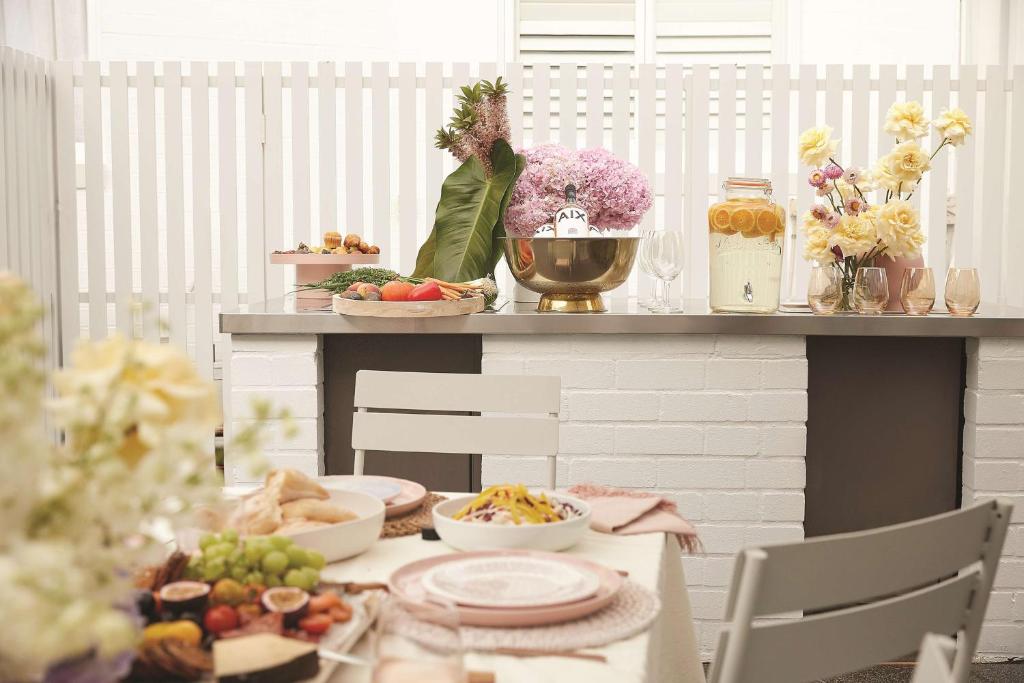 a table with plates of food and flowers on a counter at Adina Apartment Hotel Chippendale in Sydney