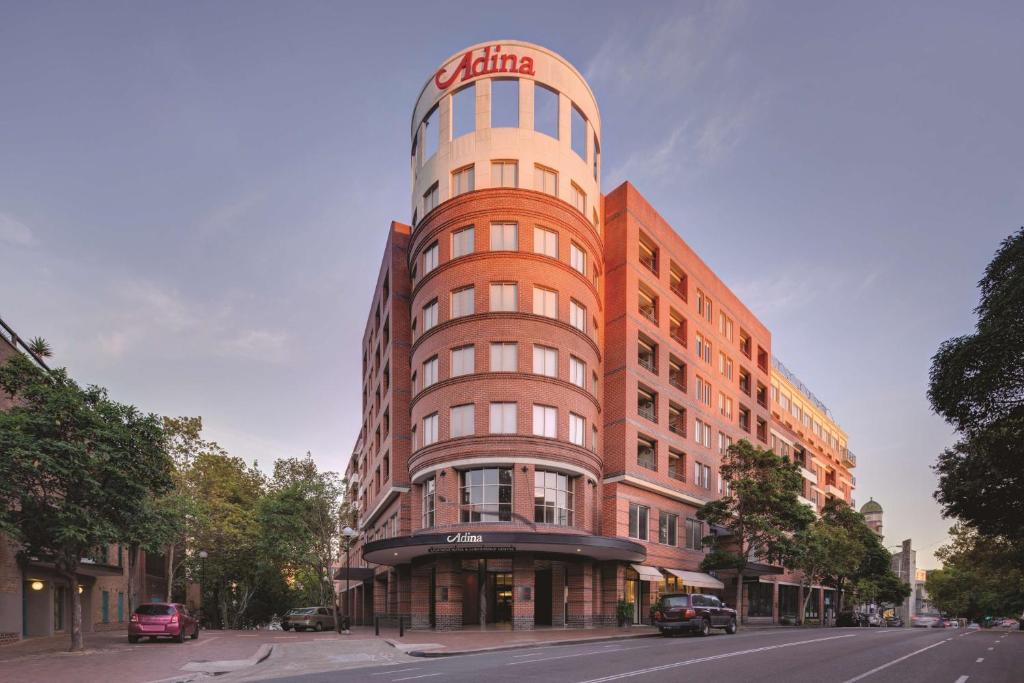 a tall building with a sign on the top of it at Adina Apartment Hotel Sydney Surry Hills in Sydney