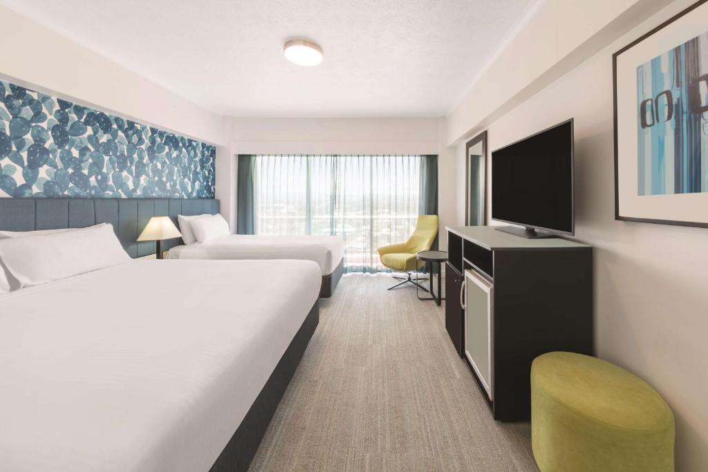 a hotel room with two beds and a flat screen tv at Vibe Hotel Gold Coast in Gold Coast