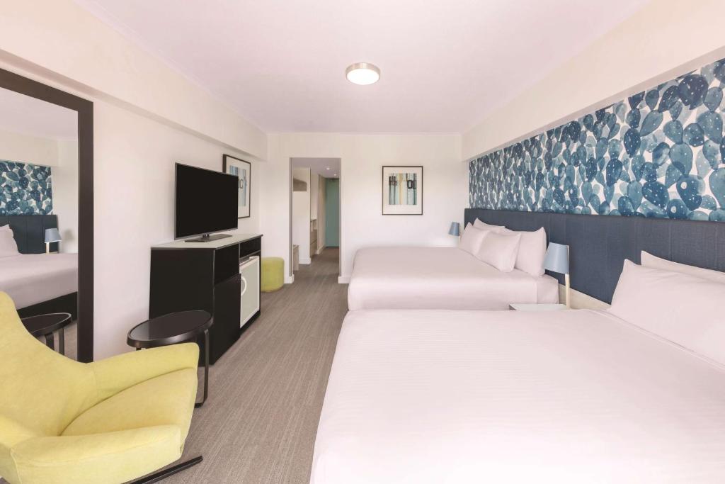 a hotel room with two beds and a tv at Vibe Hotel Gold Coast in Gold Coast