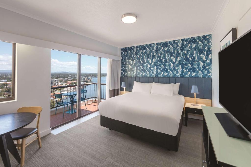a hotel room with a bed and a desk and a table at Vibe Hotel Gold Coast in Gold Coast