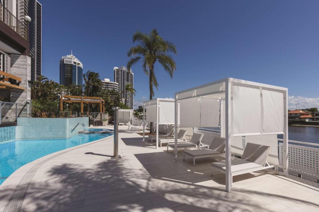 a swimming pool with lounge chairs and a canopy at Vibe Hotel Gold Coast in Gold Coast