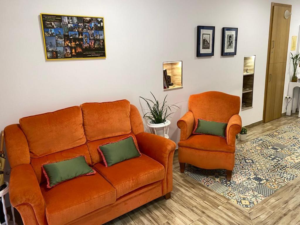 sala de estar con sofá naranja y silla en HOSTAL LA BATUTA, en Moixent (Mogente)