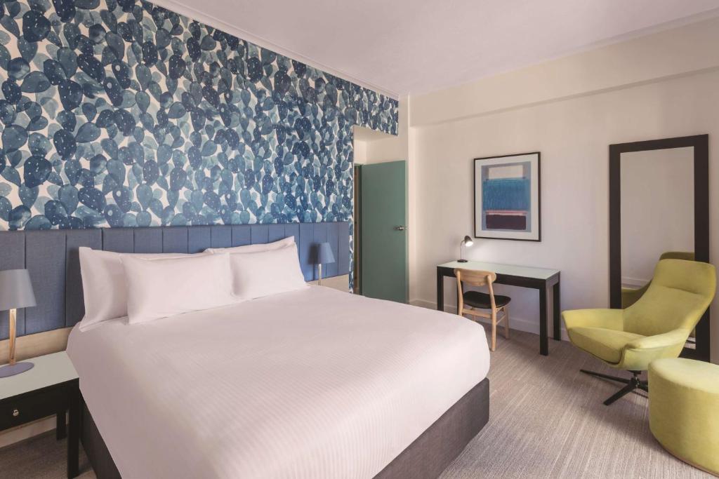 a hotel room with a bed and a desk and a chair at Vibe Hotel Gold Coast in Gold Coast