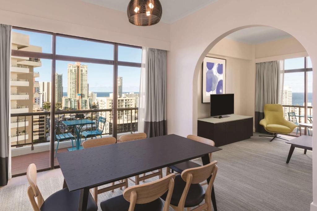 a living room with a table and chairs and a large window at Vibe Hotel Gold Coast in Gold Coast