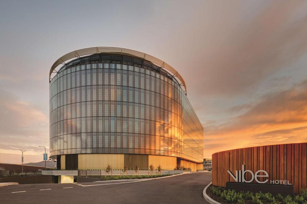 a large glass building with a sunset in the background at Vibe Hotel Canberra in Canberra