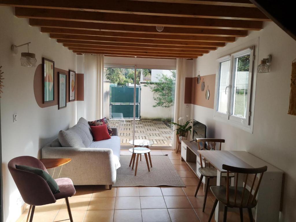 a living room with a couch and a table and chairs at Maisonnette de Charme à 10min de Fontainebleau in Héricy