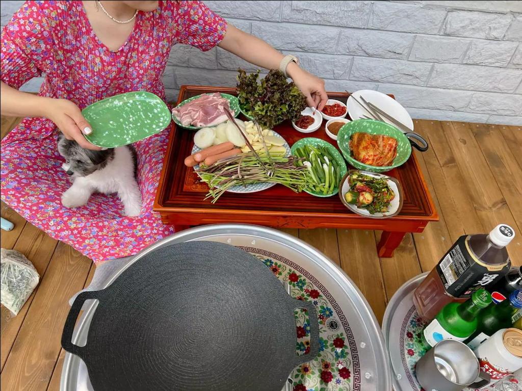 a woman and a cat sitting at a table with food at Gwanganri Grandma House in Busan