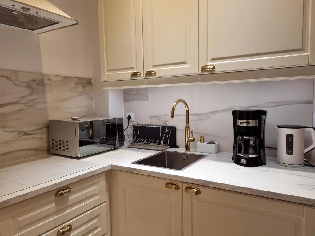 a kitchen with white cabinets and a sink and a microwave at Apartament w kamienicy in Poznań