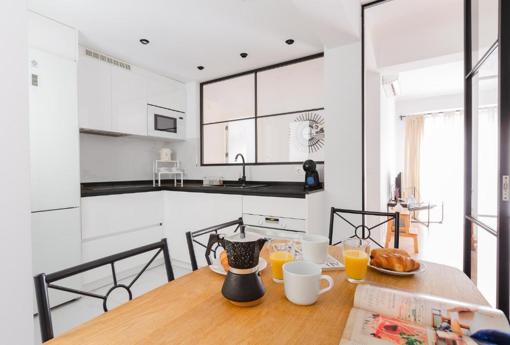 eine Küche mit einem Holztisch mit Tassen Orangensaft in der Unterkunft Malagaflat Design Apartment 3 Bedrooms City Centre in Málaga