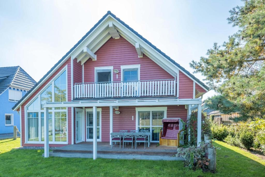 a red house with a deck and a table at Born - Wieck DAT SCHWEDENHUS EG-Whg. WI-4.1 in Wieck