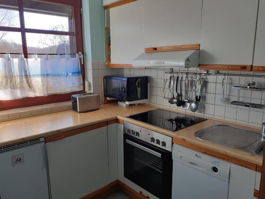 a kitchen with a stove and a microwave at Gemütliche FeWo Bi-Uns in Gustow