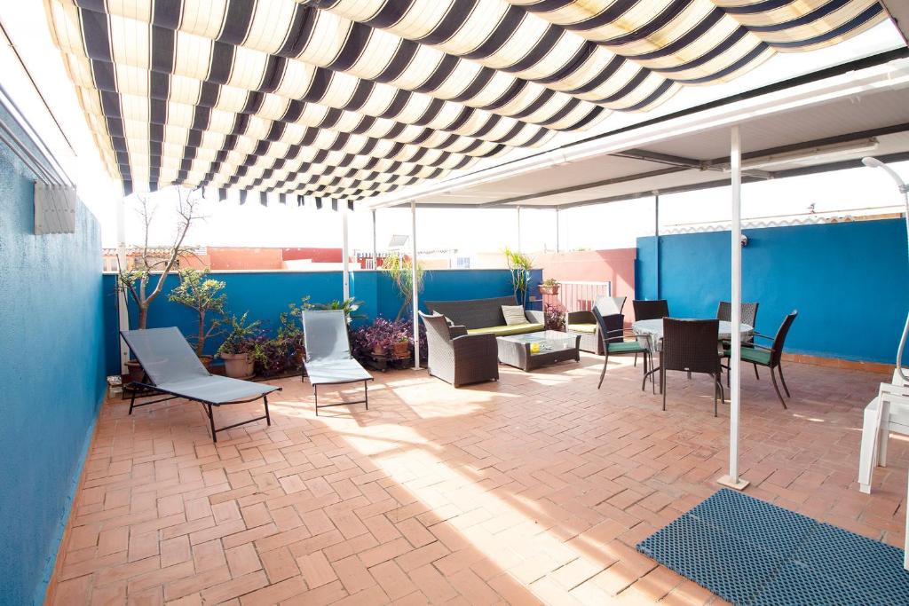 un patio con sedie e tavoli su una parete blu di Global Properties, Atico con gran terraza y barbacoa a Canet de Berenguer