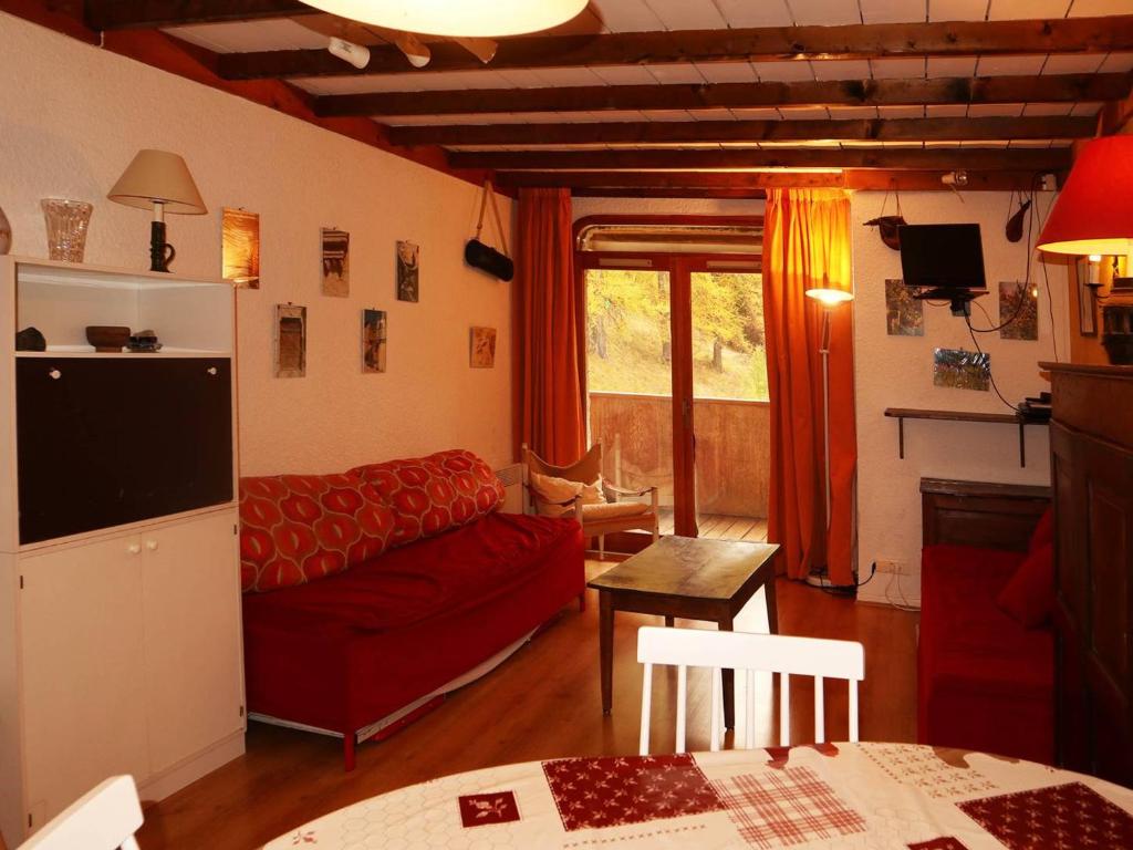 uma sala de estar com um sofá vermelho e uma mesa em Appartement Les Orres, 2 pièces, 6 personnes - FR-1-322-203 em Les Orres