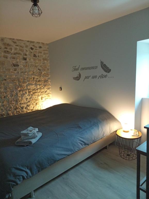 una camera con un letto e un muro in pietra di La poule aux oeufs dort a Soudan