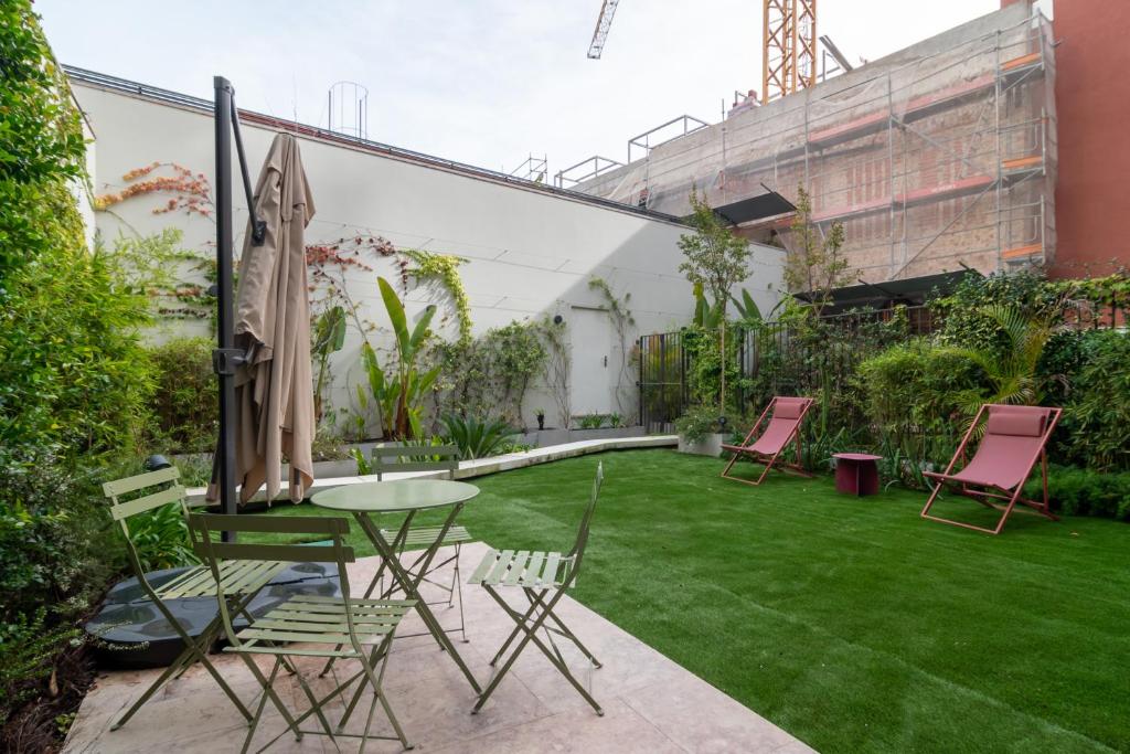 een patio met een tafel, stoelen en gras bij Liberdade Garden & Indoor Pool by LovelyStay in Lissabon
