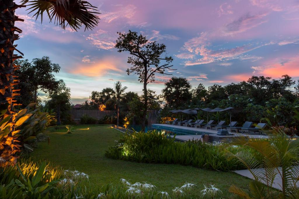 a backyard with a pool and chairs at sunset at Sala Lodges in Siem Reap