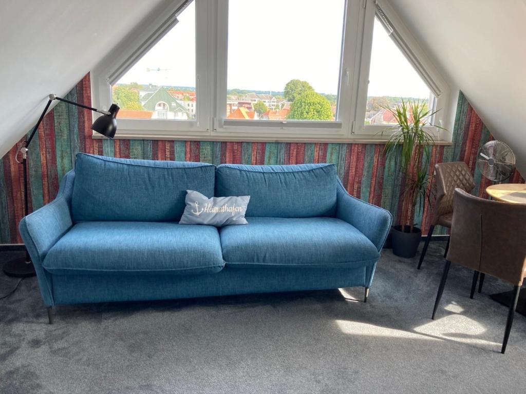 ein blaues Sofa im Wohnzimmer mit Fenstern in der Unterkunft Urban Nature13 in Grömitz