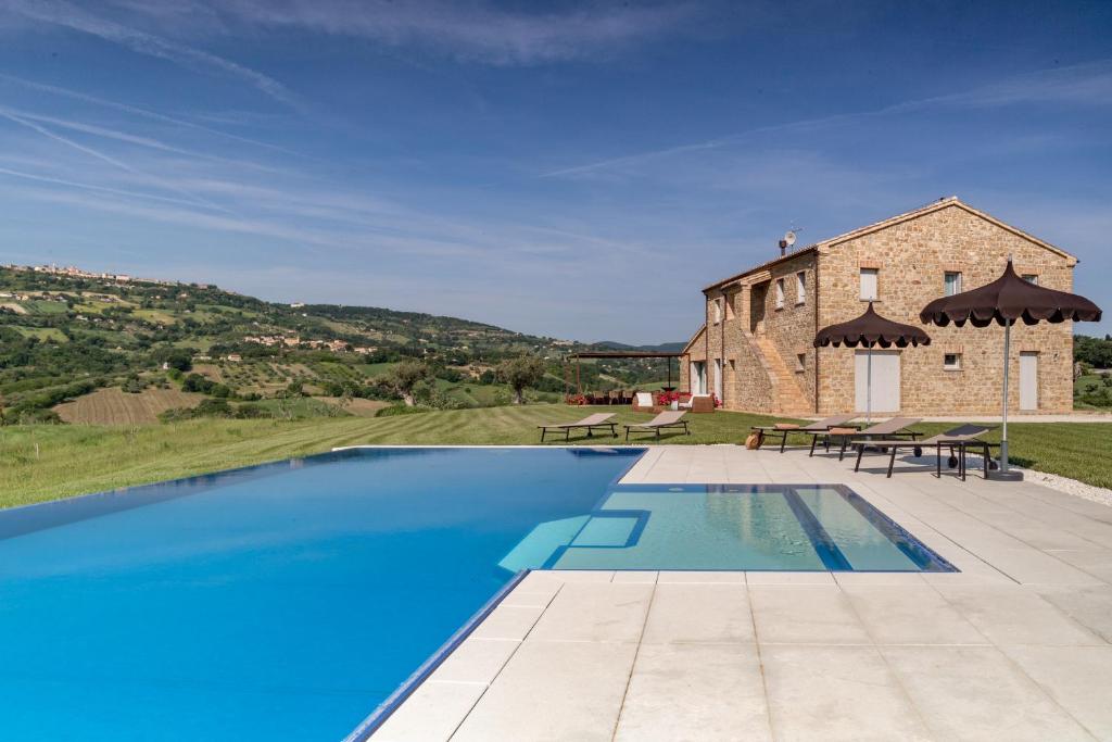 an external view of a stone house with a swimming pool at Villa Aga - Homelike Villas in Cingoli