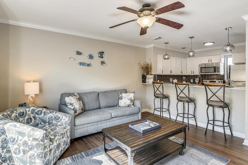 ein Wohnzimmer mit einem Sofa und einem Tisch in der Unterkunft 1BR Townhouse on Okaloosa Island - 5 Min Walk to Beach! Near Restos! in Fort Walton Beach