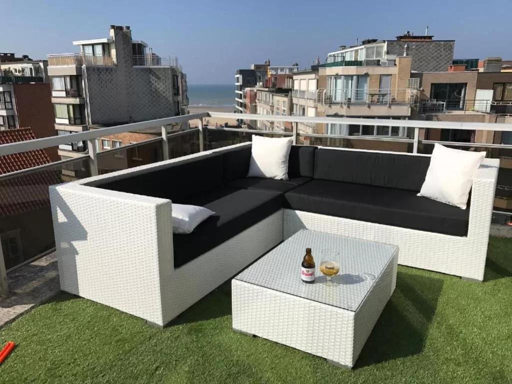 a white couch and a table on a rooftop at Penthouse VI in Koksijde