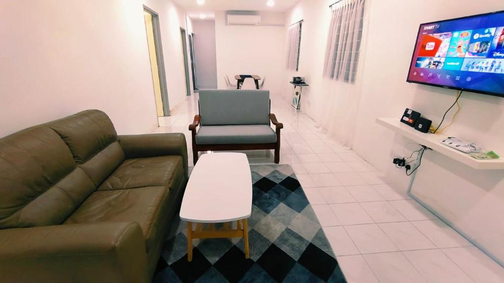 a living room with a couch and a table and a tv at 3810 Corner Tmn Putri Kulai 3BR 10pax SingleStyHouse near kulai AEON, JPO in Kulai