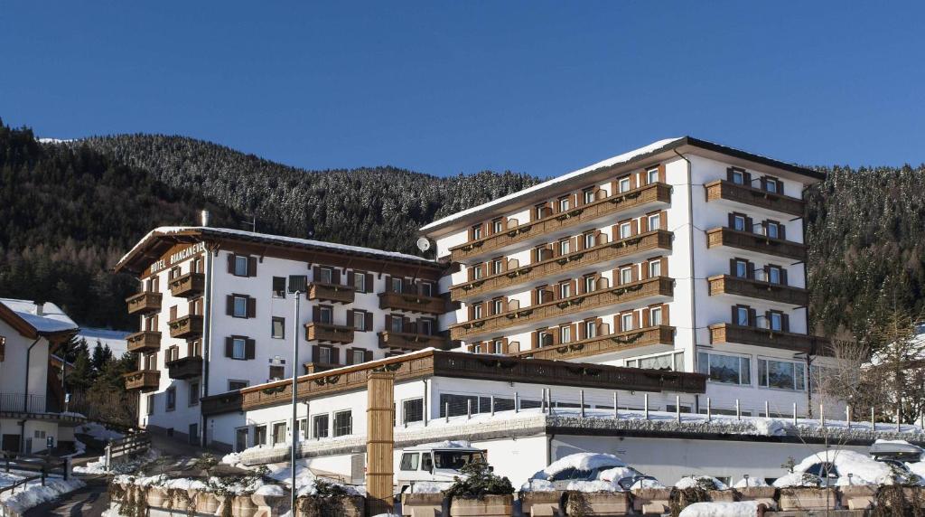 a large white building in front of a mountain at Grand Hotel Biancaneve in Folgaria