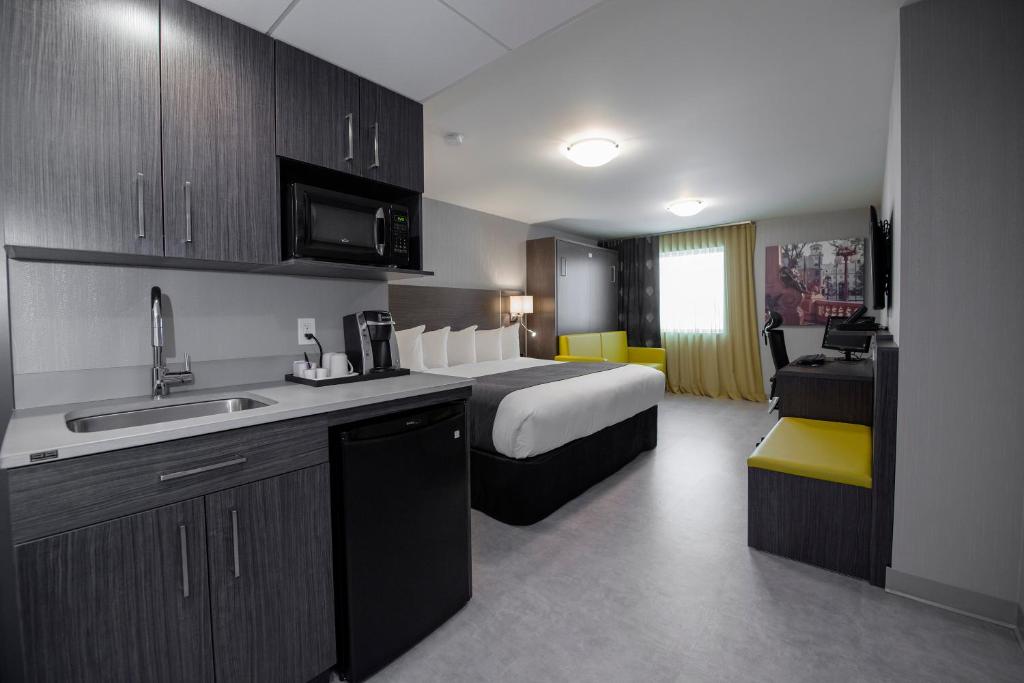 a hotel room with a bed and a kitchen with a sink at Hôtel & Suites Le Dauphin Québec in Quebec City