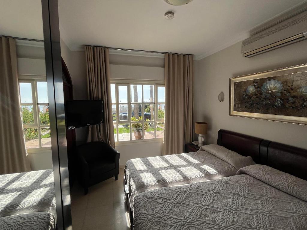 a bedroom with a bed and a chair and windows at Hotel Paraíso Del Mar in Nerja