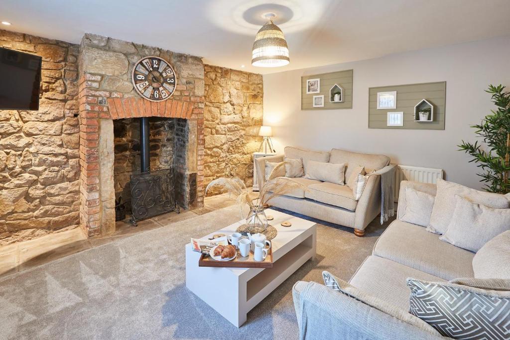 een woonkamer met een stenen muur en een open haard bij Host & Stay - Sion Hall Cottage in Alnwick