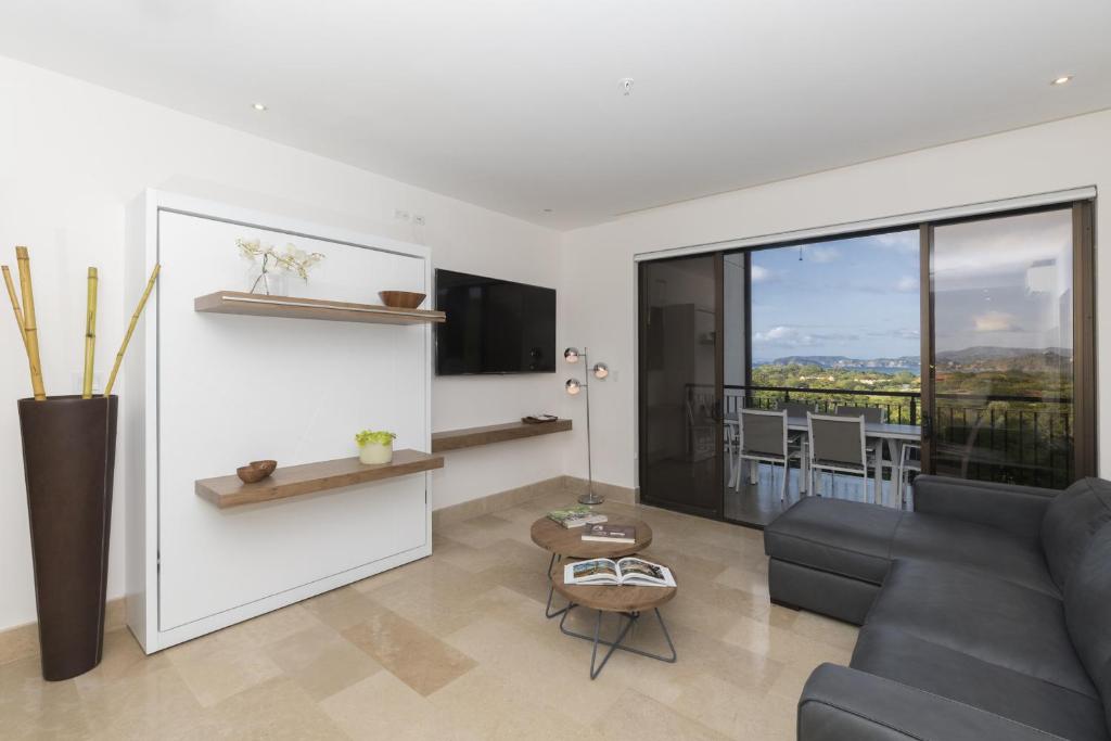 sala de estar con sofá y ventana grande en Roble Sabana 202 Luxury Apartment - Reserva Conchal, en Playa Conchal