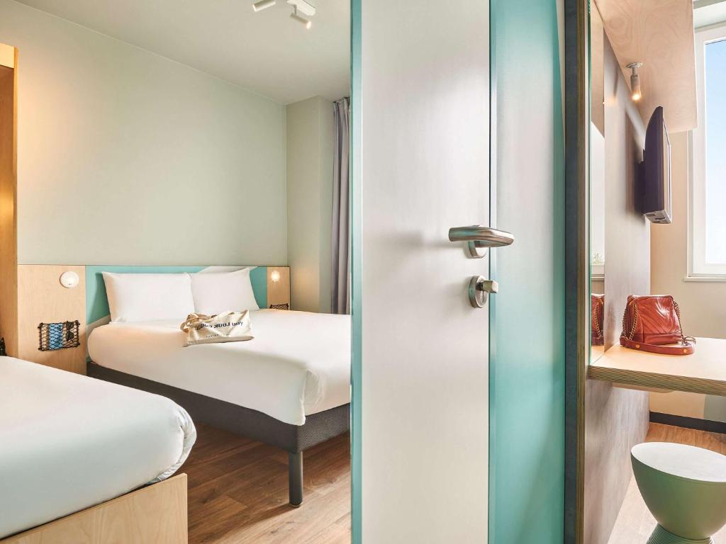ein Hotelzimmer mit einem Bett und einem Bett sowie einem Zimmer in der Unterkunft ibis budget Nancy Laxou in Nancy
