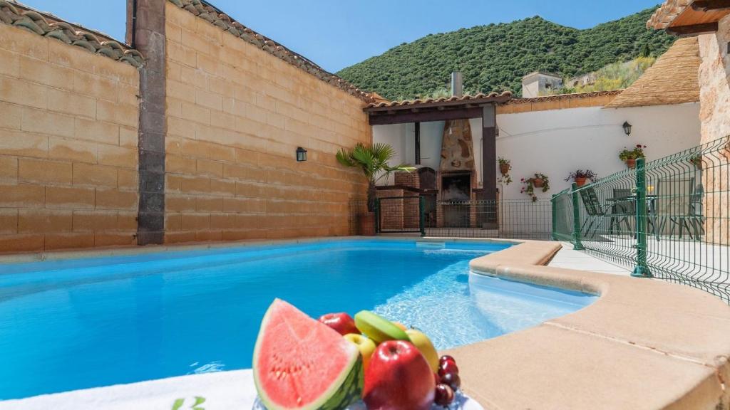 una piscina con fruta en una mesa junto a una casa en Casa Calera Arbuniel by Ruralidays, en Jaén