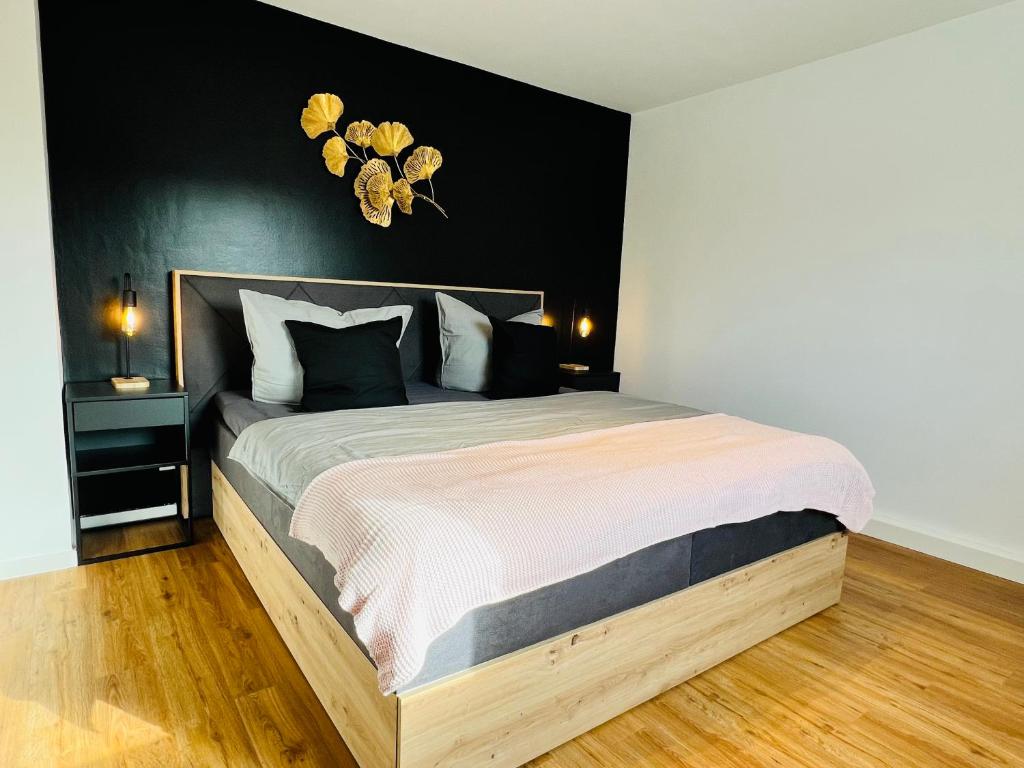a bedroom with a large bed with a black wall at Shadow Sleep in Schonungen