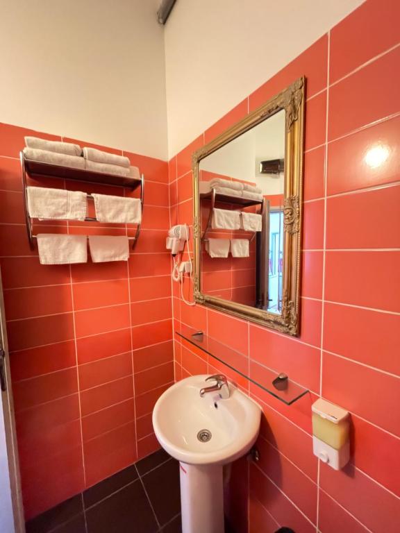 a red bathroom with a sink and a mirror at The Only One Apartments in Niš