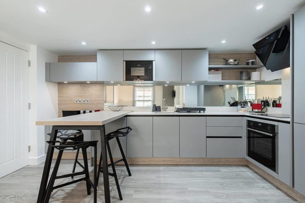 a kitchen with white cabinets and a table with stools at Flat 3, 158 Abingdon Road in Oxford